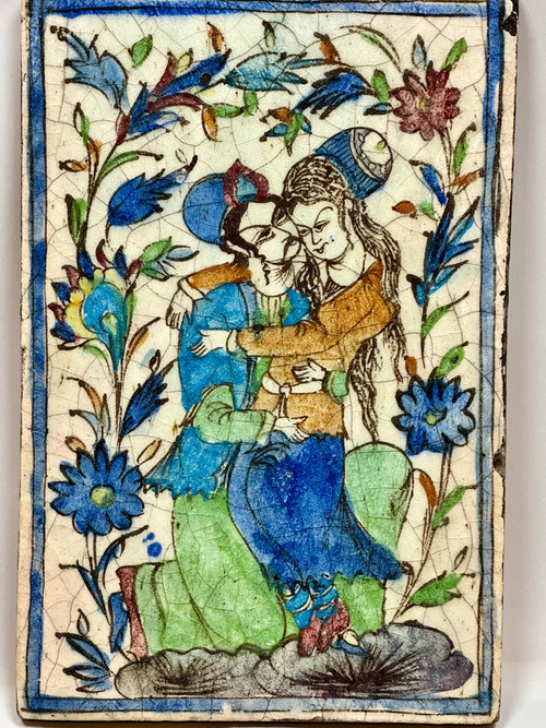 Enamelled tile representing an embracing couple in a stylized garden