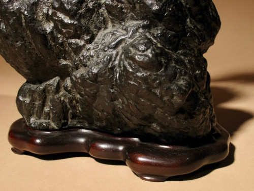 A highly decorative bronze model of a hawk sitting on a steep rock.