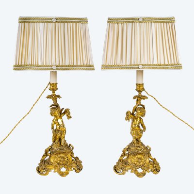 A pair of Napoleon III period gilt bronze Putti candlesticks, mounted as lamps