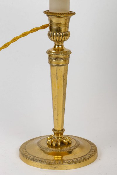 A pair of French Directoire period candlesticks converted as table lamps in chiseled and gilt bronze