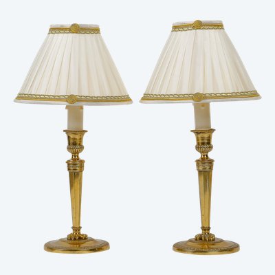 A pair of French Directoire period candlesticks converted as table lamps in chiseled and gilt bronze