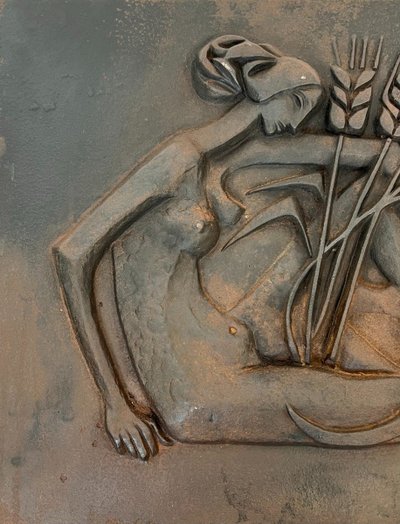 Modernist cast-iron plaque depicting a Nude Woman Holding a Scythe and Wheat Spikes.