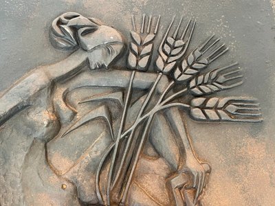 Modernist cast-iron plaque depicting a Nude Woman Holding a Scythe and Wheat Spikes.