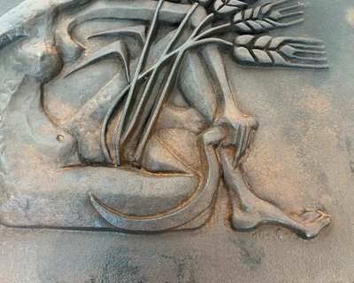 Modernist cast-iron plaque depicting a Nude Woman Holding a Scythe and Wheat Spikes.