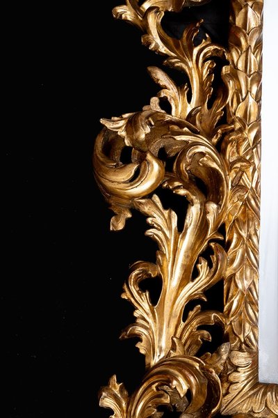 Antique mirror with scrolls in gilded and carved wood. Florence, 18th century.