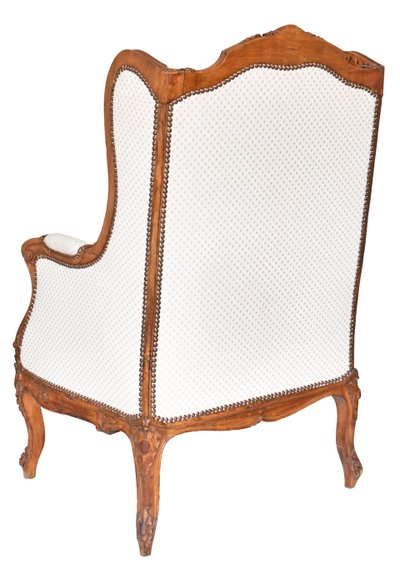 Louis XV style wing chair in richly carved wood