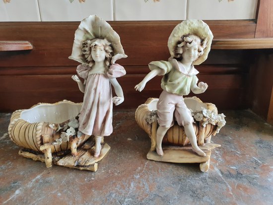 Bohemian-style porcelain figurines of children with shallow bowls, decorated with applique flowers dating to around 1900