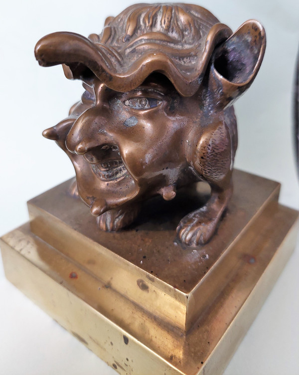 Old inkwell in gilded bronze on a base with the head of a laughing monster