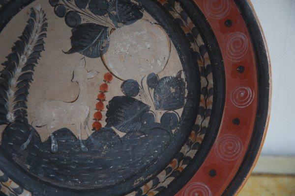 Large circular terracotta dish decorated with a fawn in a landscape.