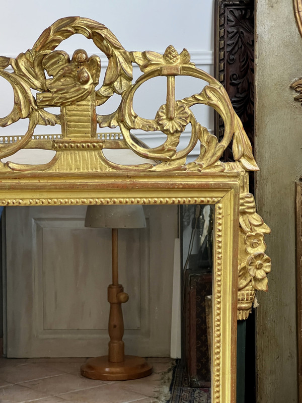 MIROIR EN BOIS SCULPTÉ DORÉ AVEC FRONTON AJOURÉ A DECOR DE FLEURS STYLE L.XVI