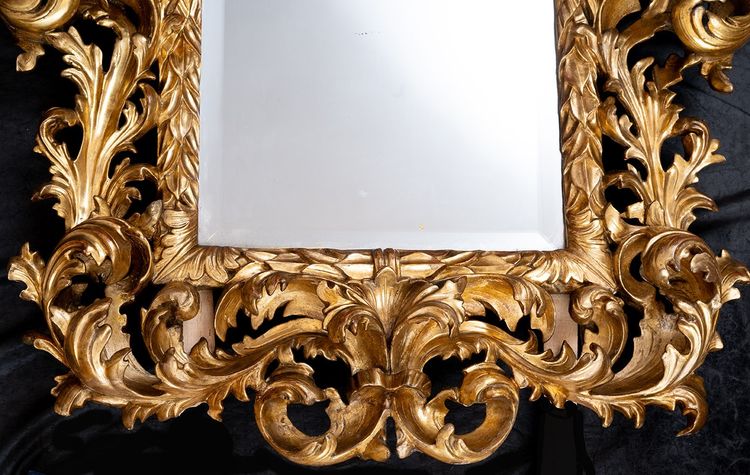 Antique mirror with scrolls in gilded and carved wood. Florence, 18th century.